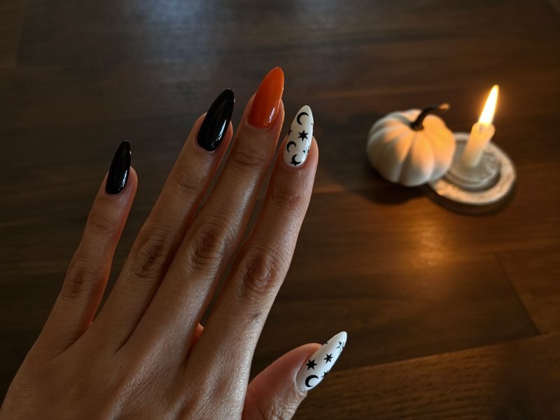 Almond Halloween nails in black, burnt orange and milky white with tiny moons and stars