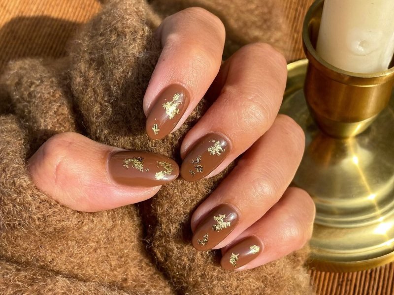 Brown and gold fall nails on medium almond nails with espresso polish and gold foil flakes