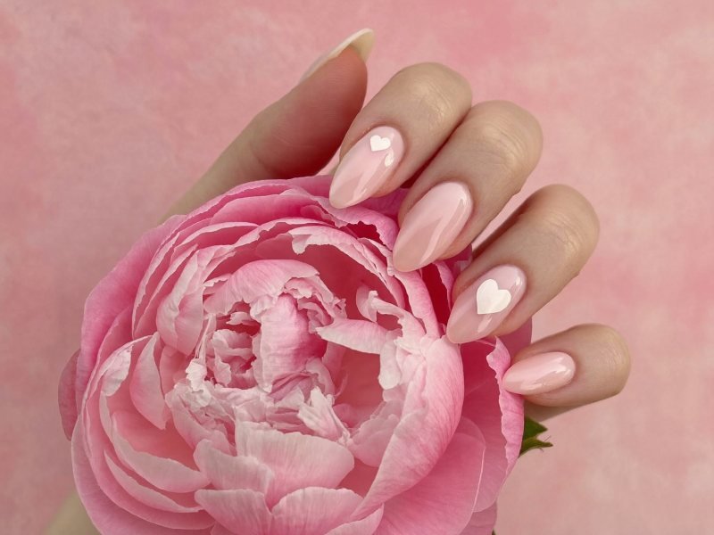 Cute nail designs: short pink nails with tiny white hearts on two fingers