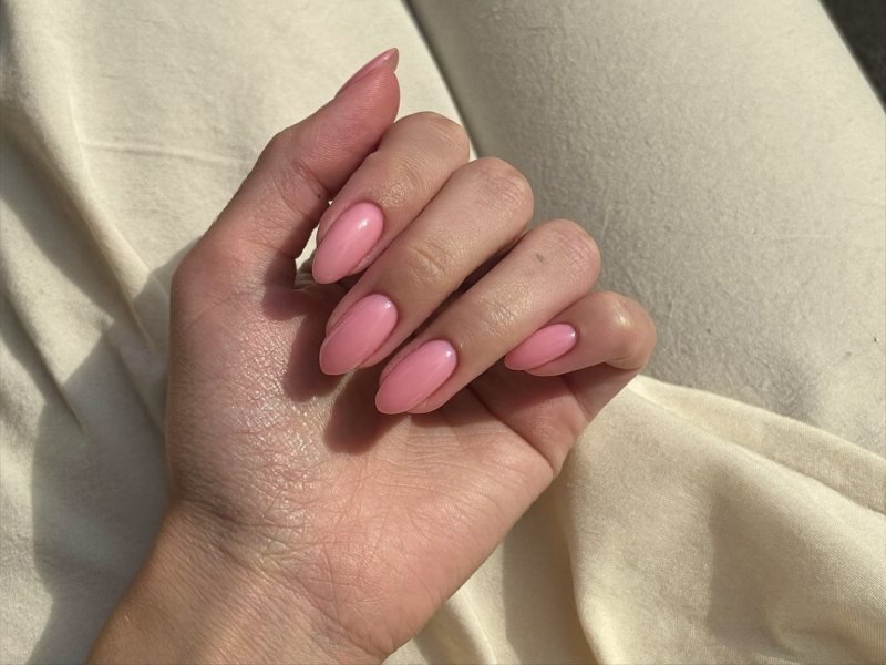 Finished hand wearing short almond press-on nails in soft pink