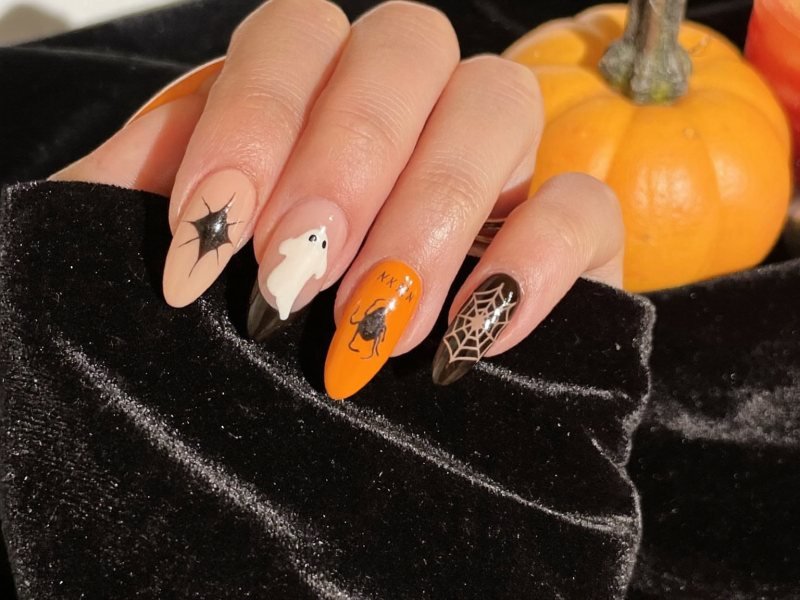 Halloween nail designs on almond nails with ghosts, black tips and orange accents
