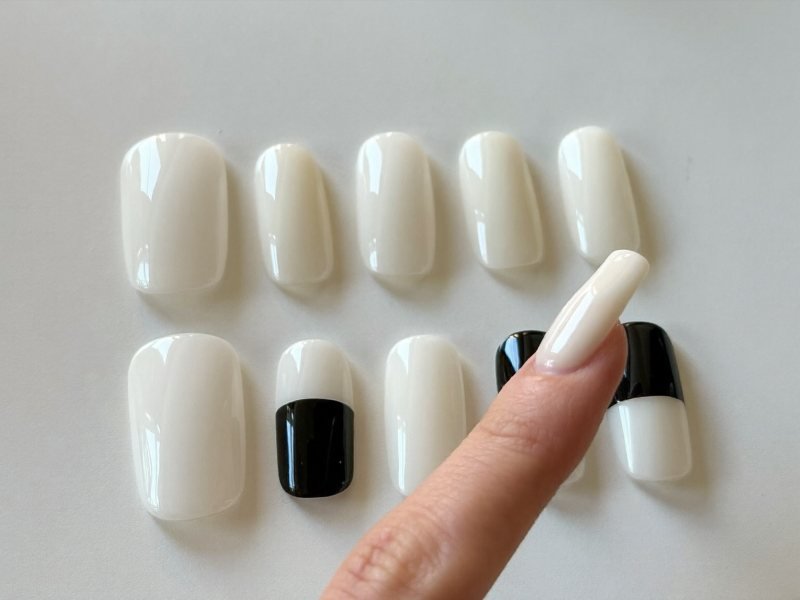 Hand choosing the right size press-on nail by holding it over the natural nail