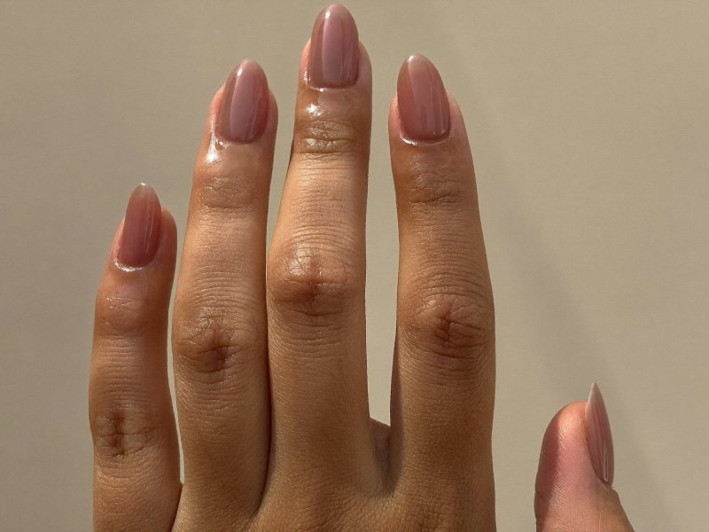 Hand with short oval nails in sheer nude showing how the shape lengthens the fingers