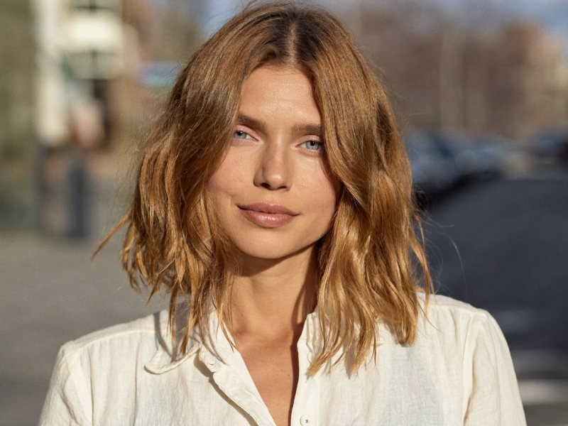 Lob haircut: a woman with a collarbone-length wavy long bob in warm caramel brown