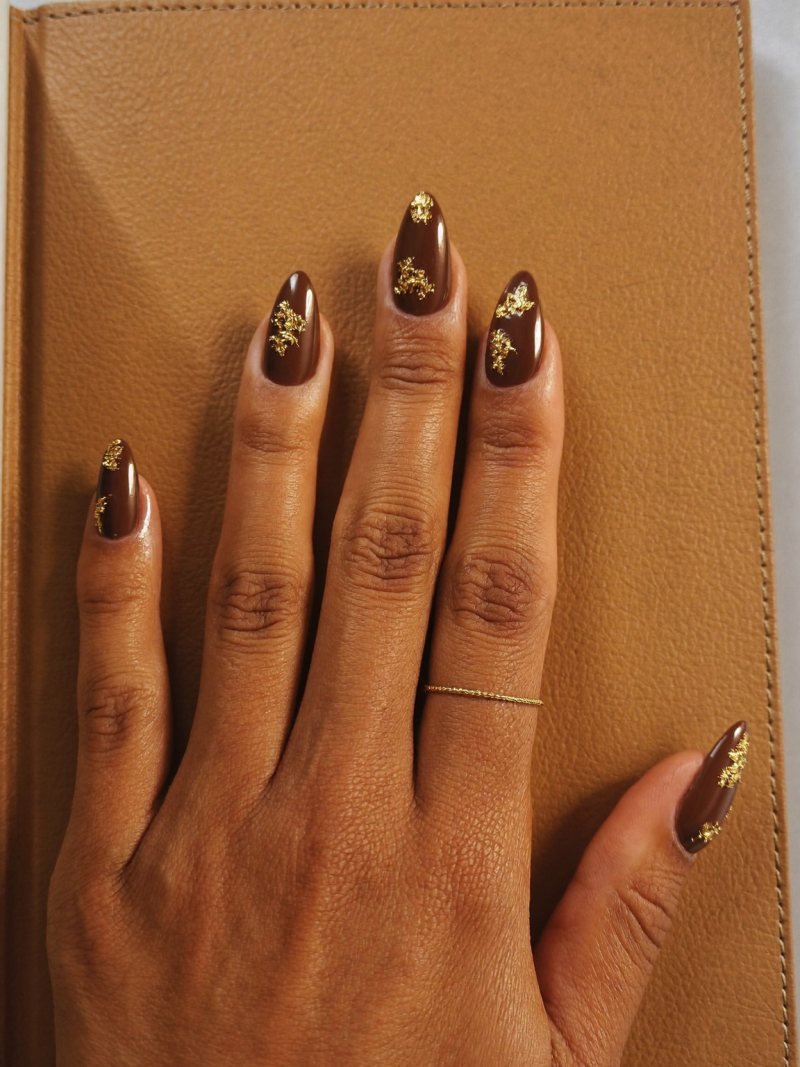 Medium almond nails in glossy espresso brown with gold foil flakes