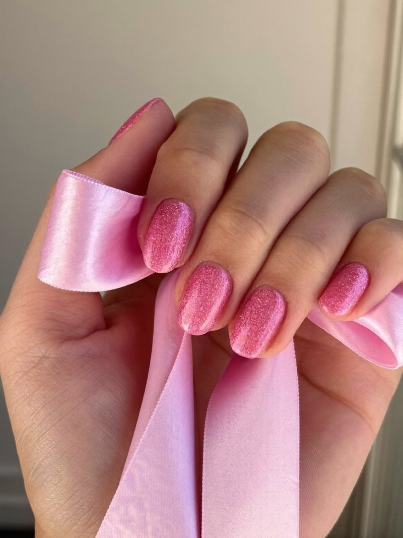 Medium almond nails in sheer pink with fine pink glitter at the tips