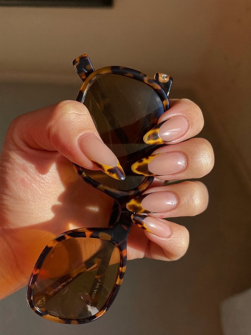 Medium almond nails with a nude base and tortoiseshell French tips