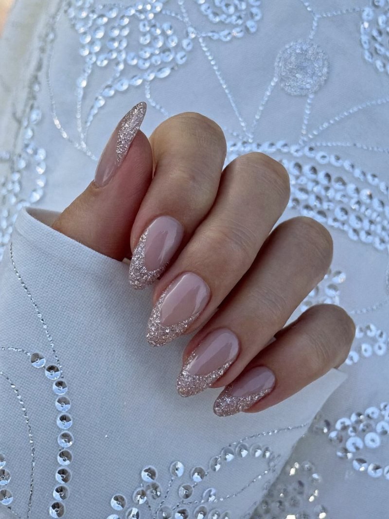 Medium almond nude nails with a fine silver glitter fade