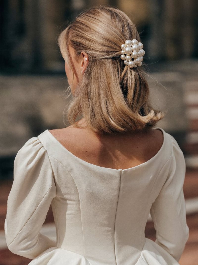 Medium blonde hair worn half up and secured with a pearl comb
