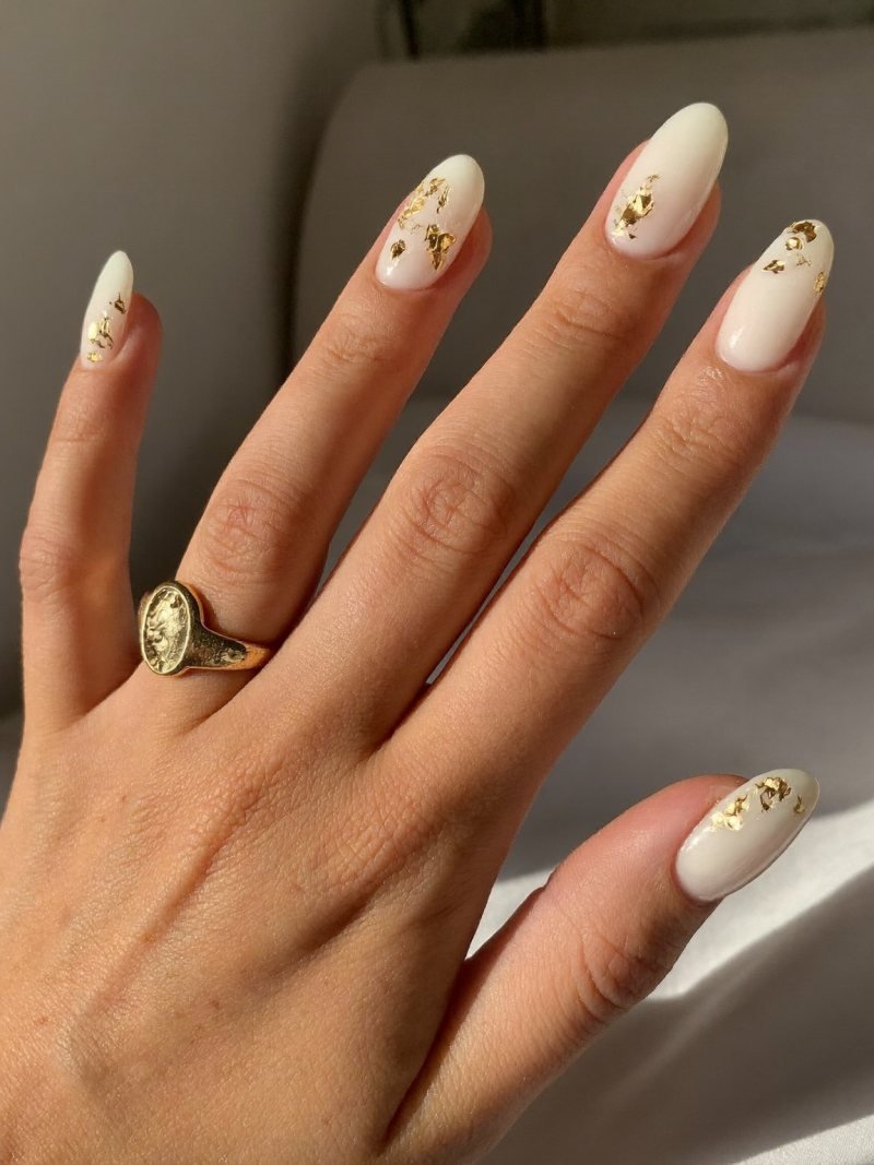 Medium oval milky white nails with small gold foil flakes