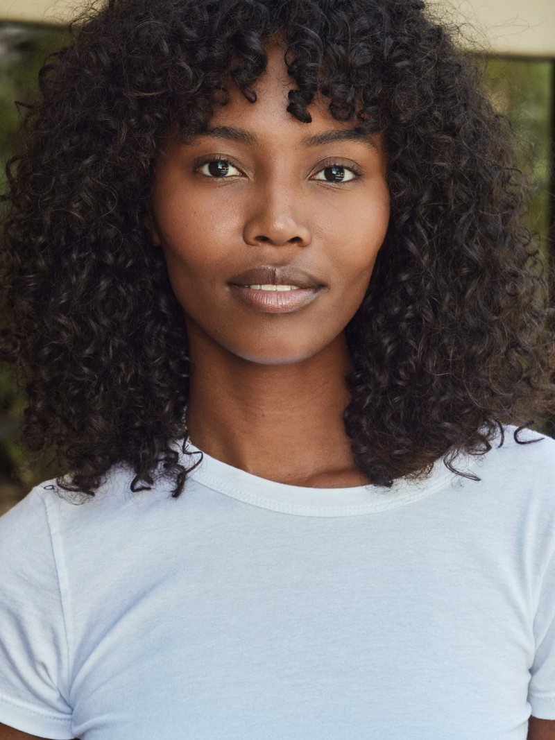 Natural curly dark hair with curly bangs on the forehead