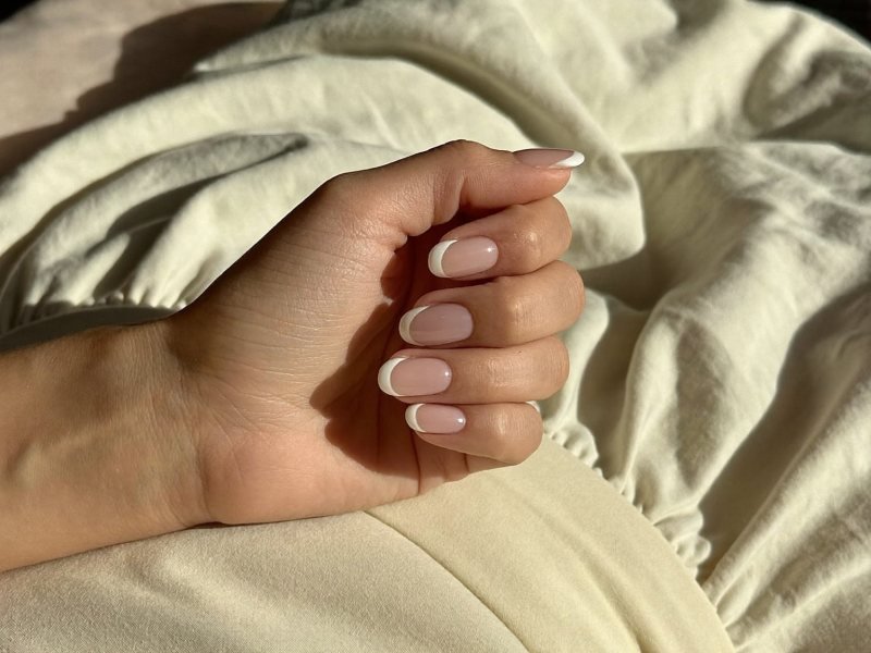 Neat classic French manicure on short oval nails after top coat