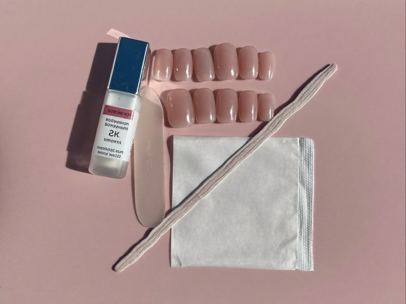 Press-on nails for beginners laid out with glue, file and cuticle stick