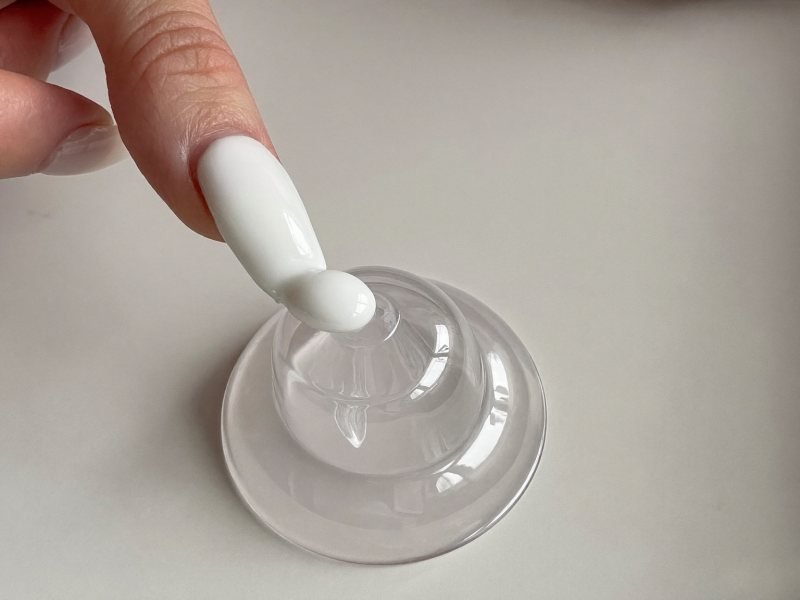 Pressing a nail tip into a silicone stamper coated with white polish to make a French tip