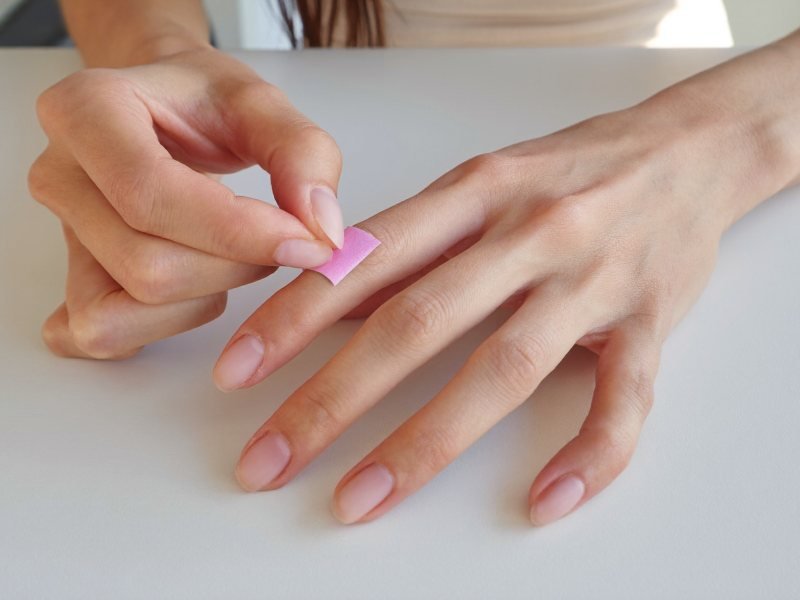 Pressing a press-on nail onto the finger at an angle from the cuticle