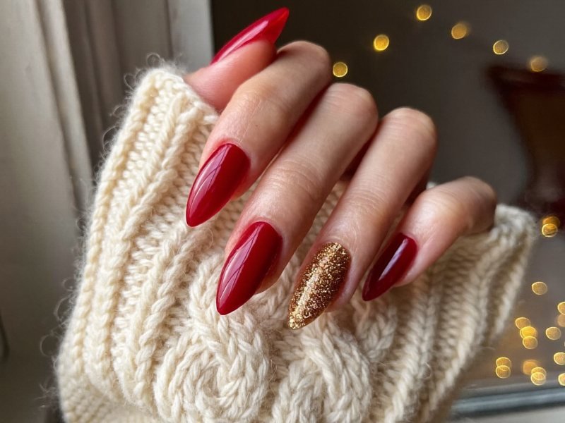 Short almond Christmas nails in deep red with one gold accent nail