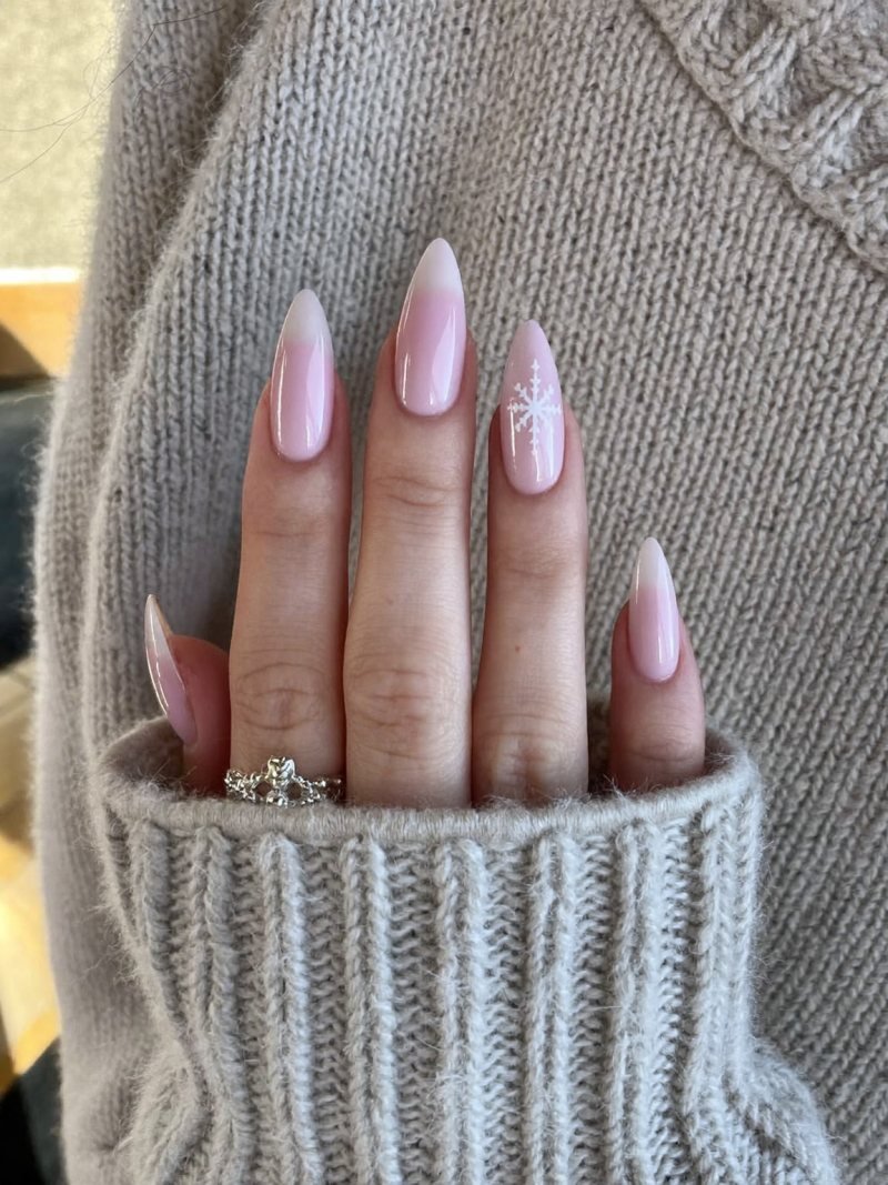 Short almond nails in sheer pink with one tiny white snowflake