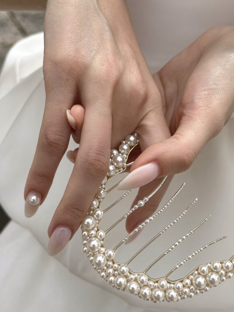 Short almond nude nails with a tiny pearl at the cuticle