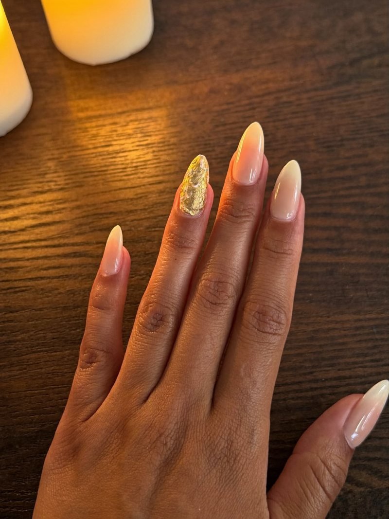 Short almond nude nails with gold leaf on the ring finger