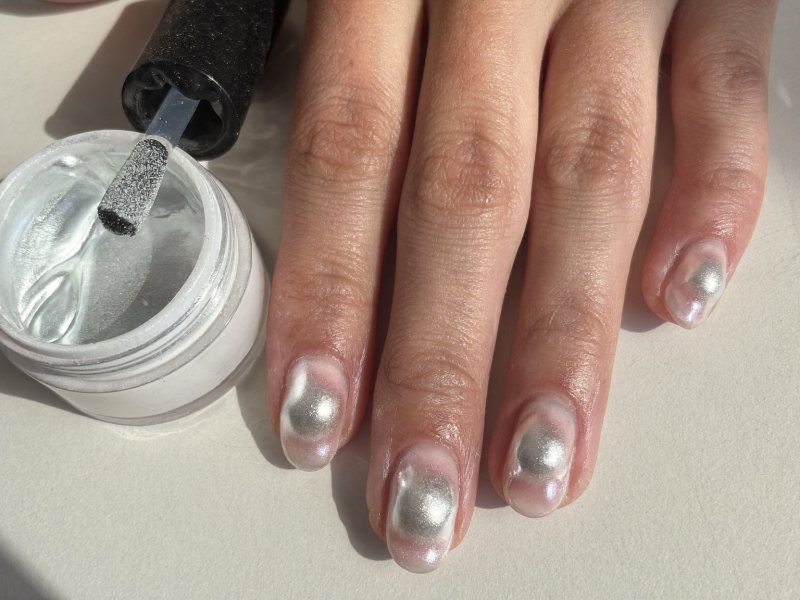 Short chrome nails with a pearly glazed finish catching the light