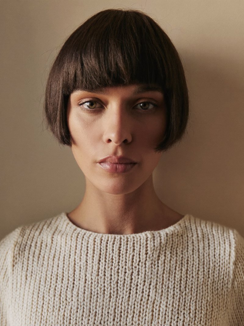 Short dark French bob at lip length with a full soft fringe