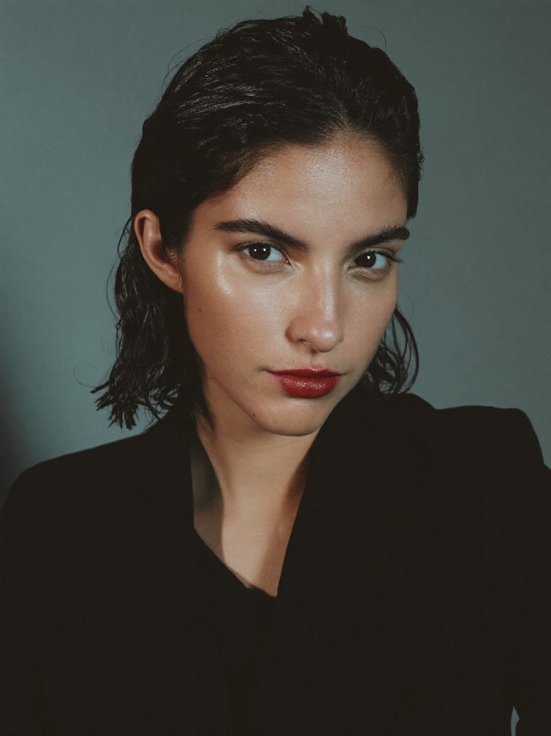 Short dark hair slicked straight back with a glossy wet-look finish