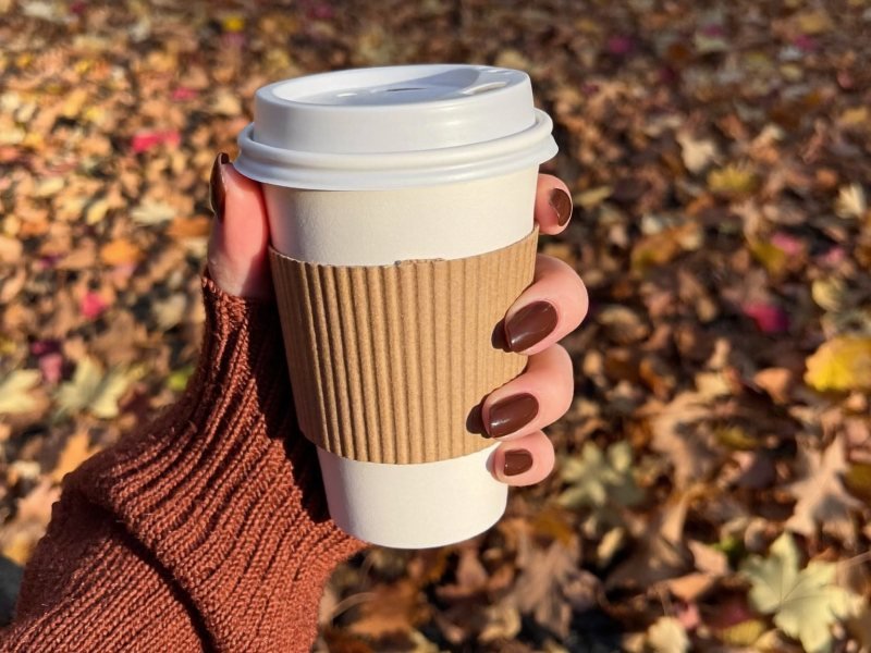 Short fall nails in glossy chocolate brown holding a coffee cup