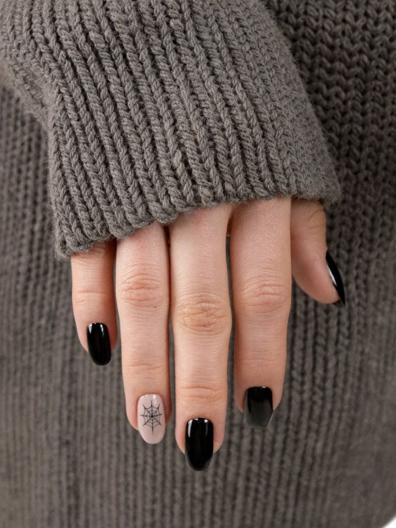 Short oval black nails with one nude nail showing a thin black spider web
