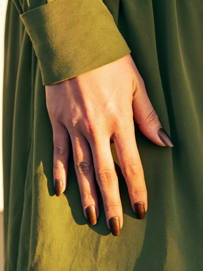 Short oval bronze shimmer nails with an olive green dress