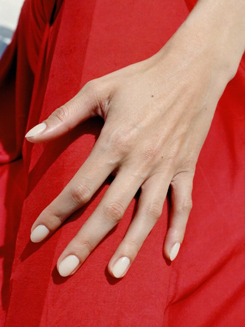 Short oval milky white nails with a red dress