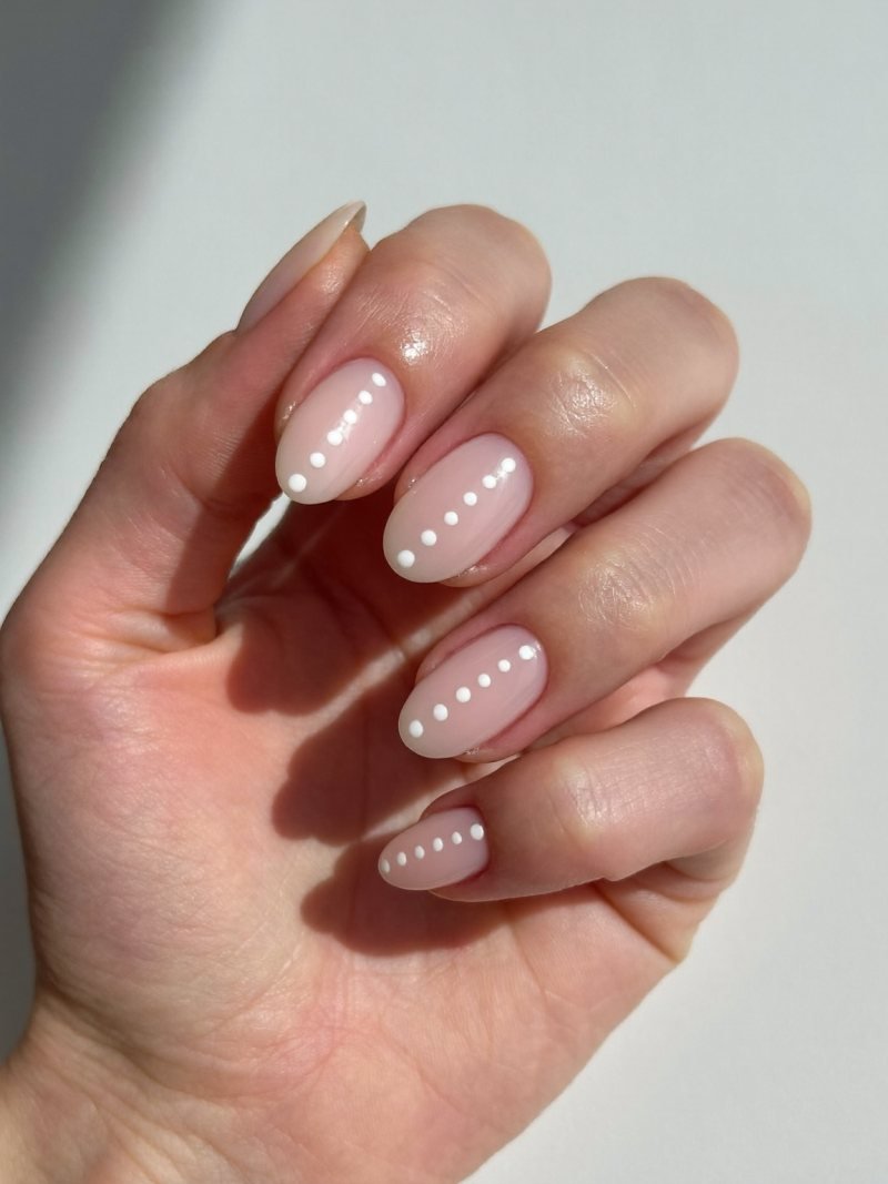 Short oval nude nails with a row of three small dots