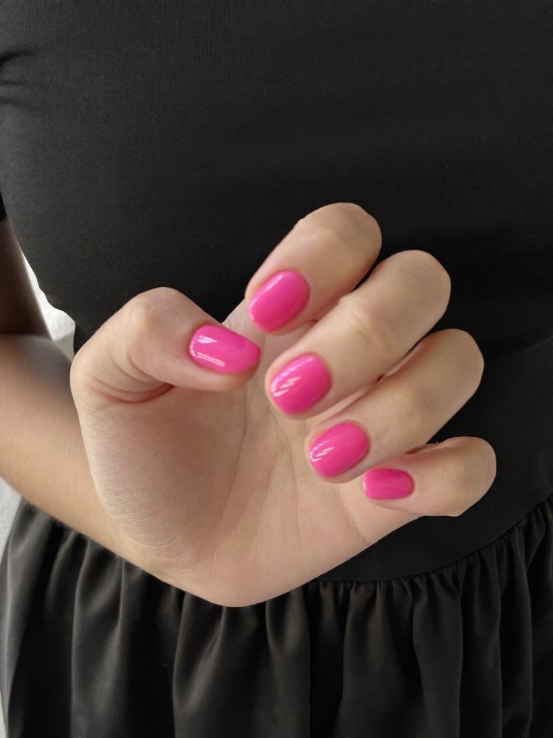 Short round hot pink nails with a black dress