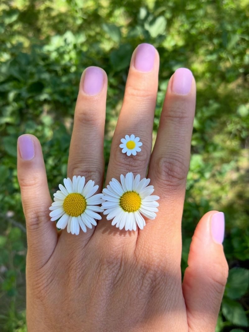 Short round lilac nails with a small white daisy on one nail