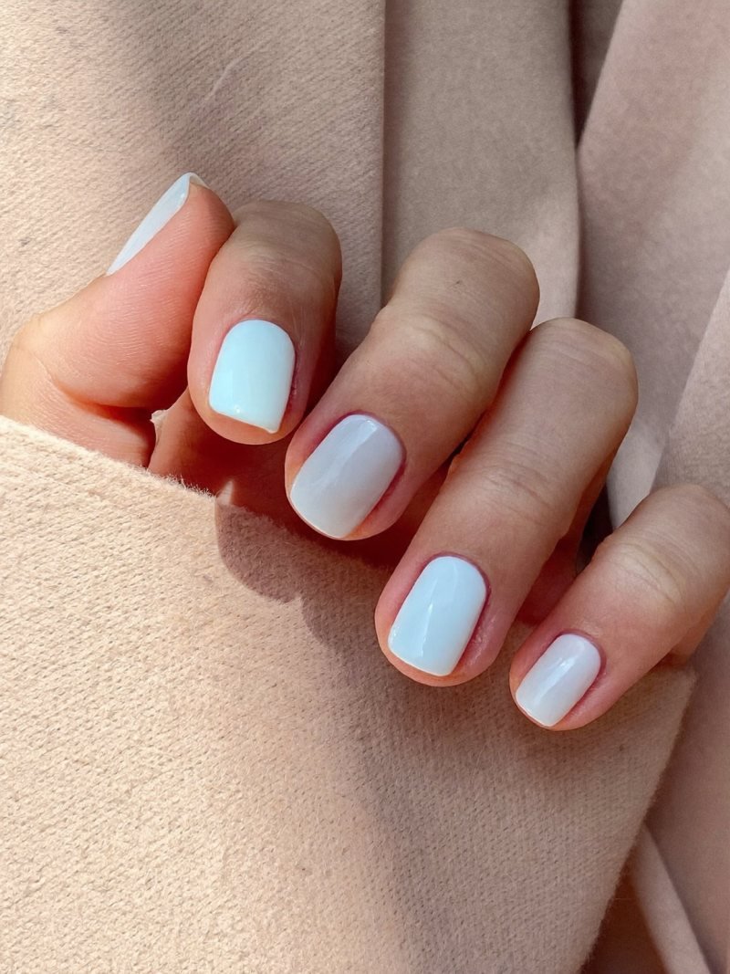 Short round pink nails with a single white accent nail