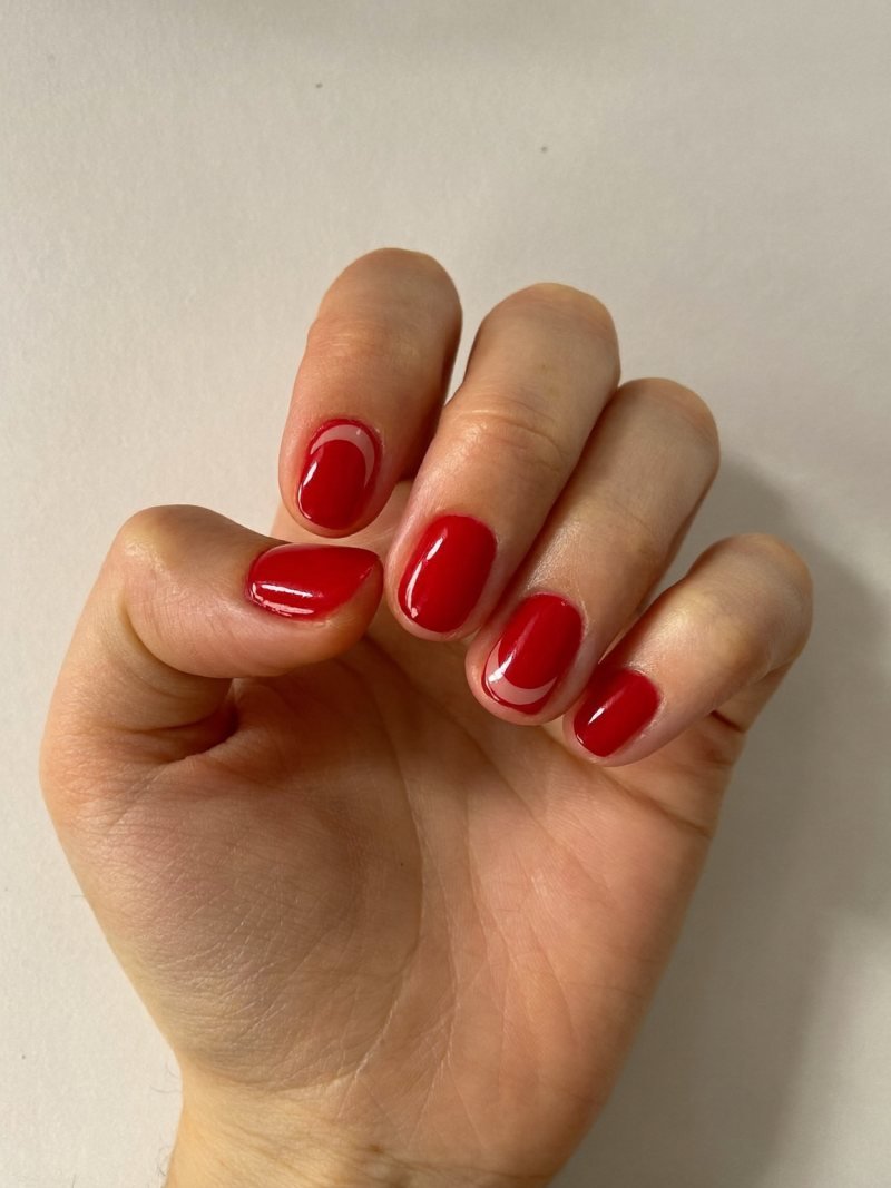 Short round red nails with a bare half-moon at the base