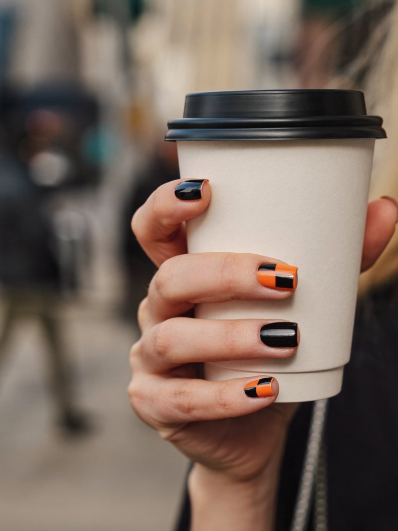 Short square nails alternating glossy black and pumpkin orange