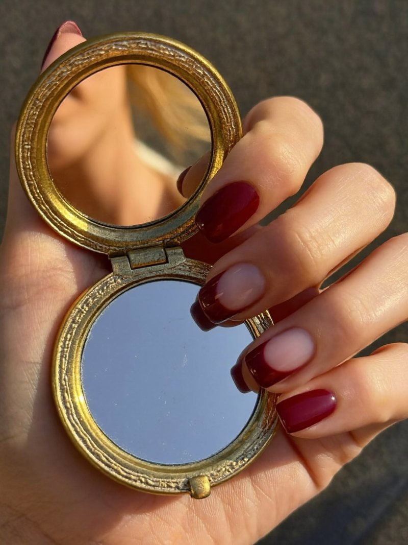 Short square nails in burgundy with a bare half-moon at the base
