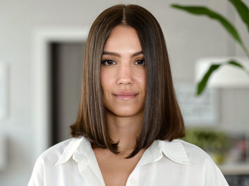 Shoulder length haircuts: a woman with a blunt collarbone-length cut in glossy dark brown