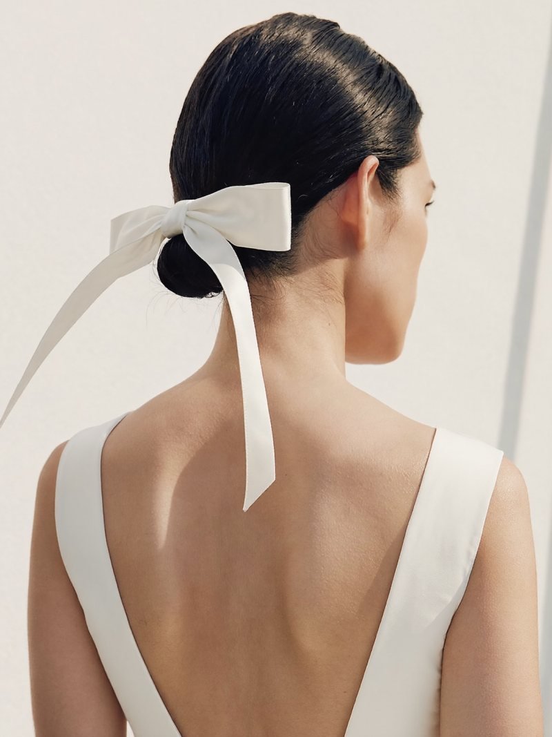 Sleek center-parted knot with a white fabric bow beneath it