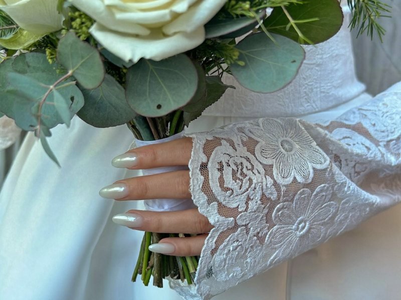 Winter wedding nails in milky white with a pearl finish holding a bouquet