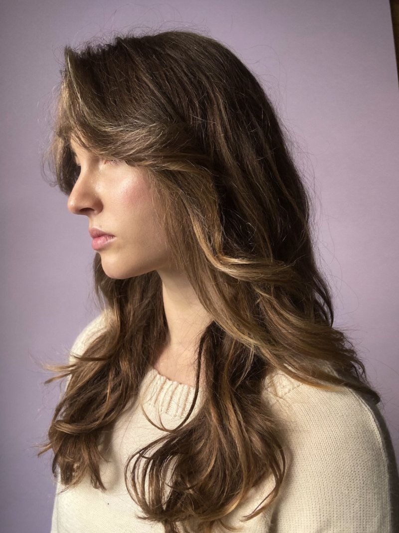 Woman with long layered hair in soft waves seen from the side